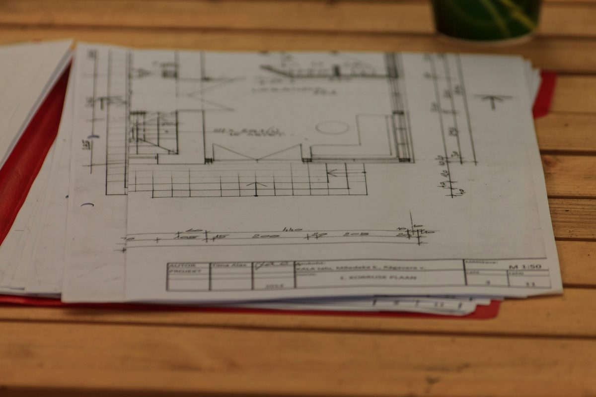Printed architectural floor plans stacked on a wooden table