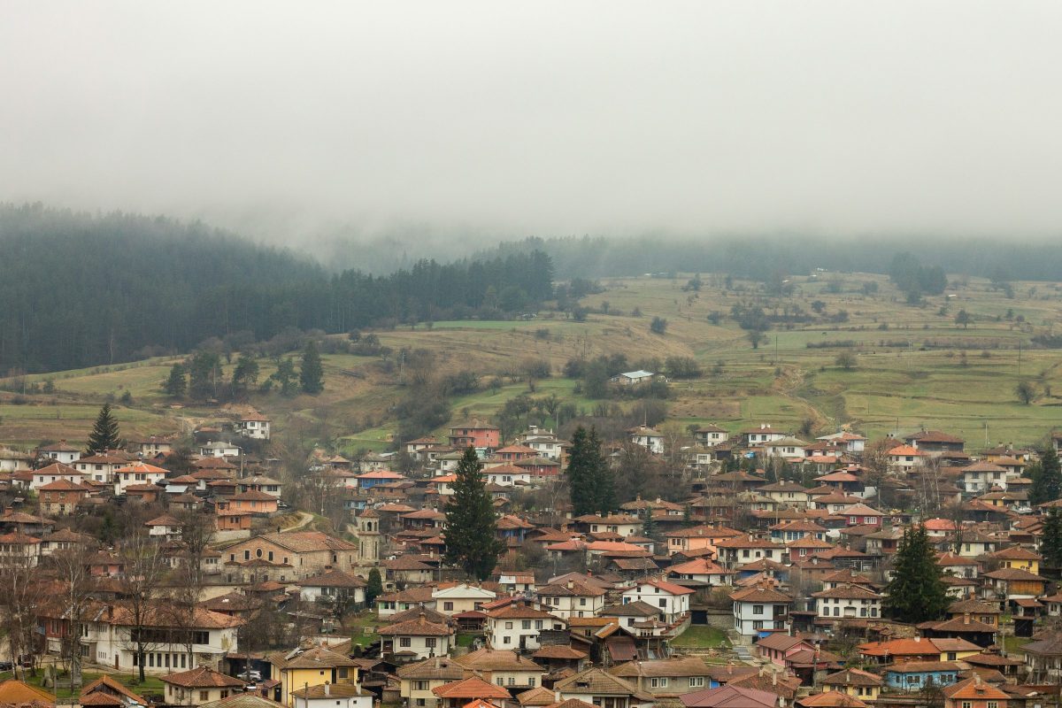 The historic town of Koprivshtitsa, Bulgaria, with tiled roofs beneath misty forested hills