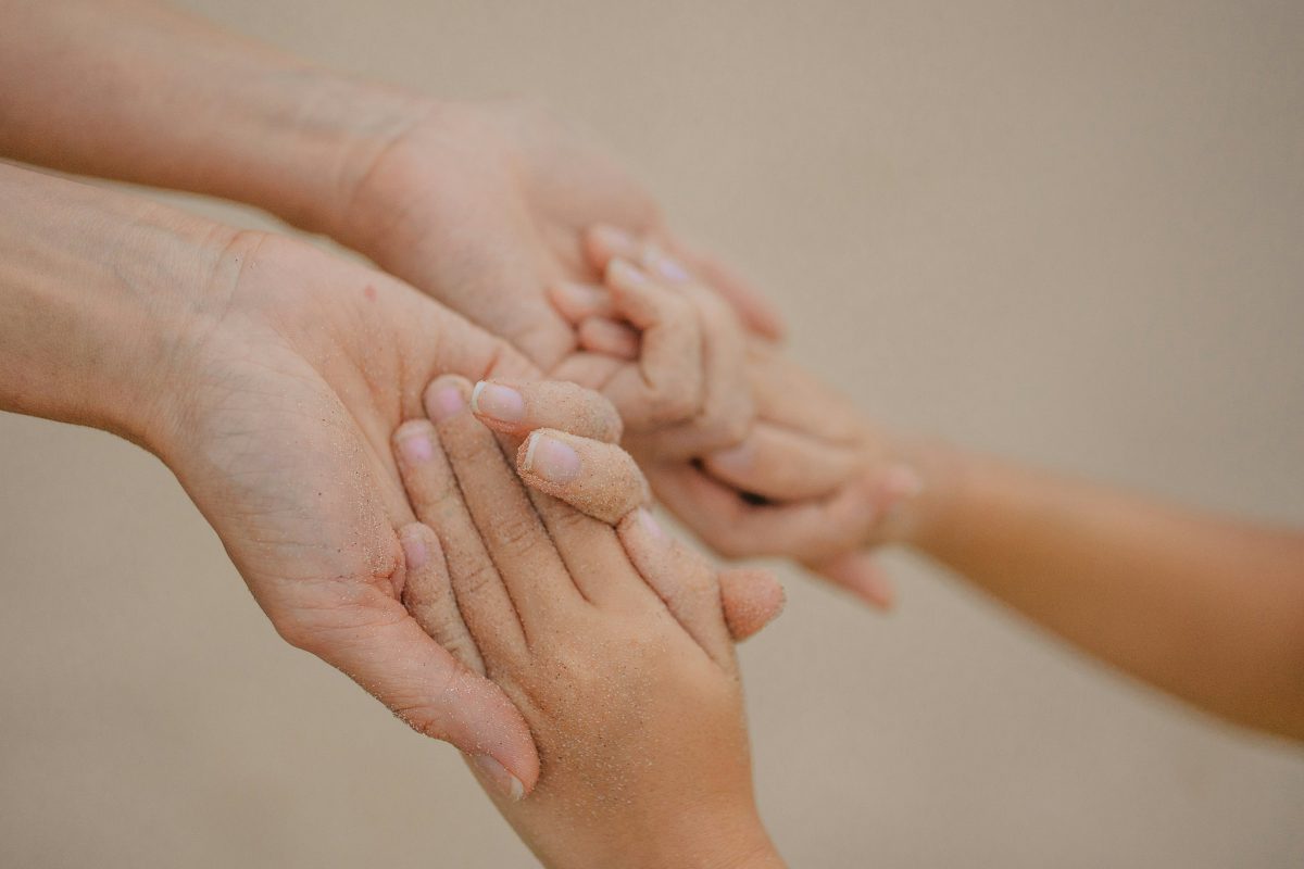 A parent gently holding a child’s hands