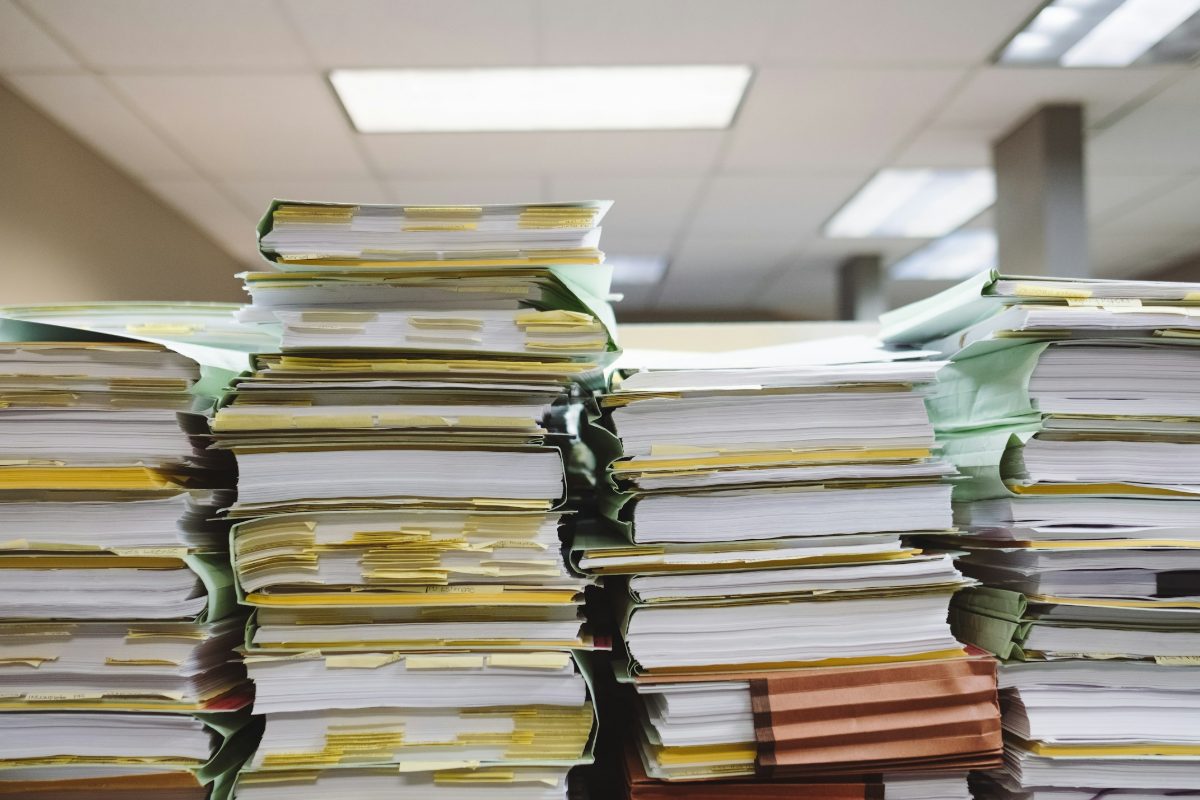 Tall stacks of paper files and folders on an office desk